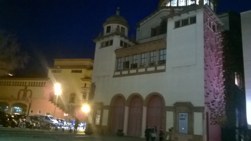 Mercat de les Flors y su cúpula iluminada con el fresco de Miquel Barceló desde el Institut del Teatre. Se puede ver la Plaça Margarida Xirgu, donde se habilita el aparcamiento gratuito, y al fondo el Teatre Lliure.